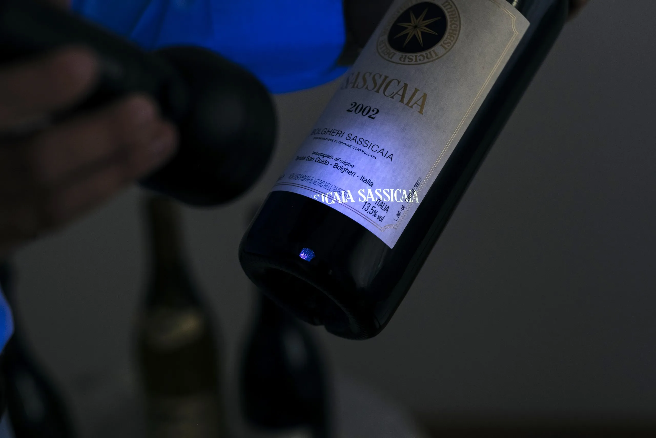 A bottle of Sassicaia 2002 checked under a torch